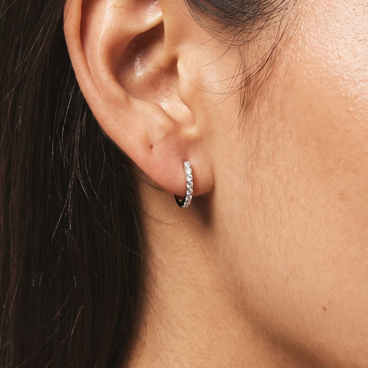 Woman wearing the Olivia Pavé Silver Hoops on her lobe, showcasing a row of tiny sparkling crystals