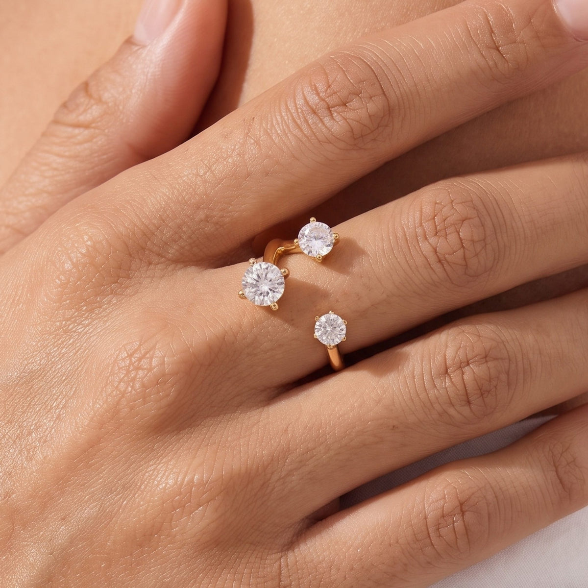 Close-up of the Open Trio Ring worn on a hand, showing its three round crystals in a gold open setting