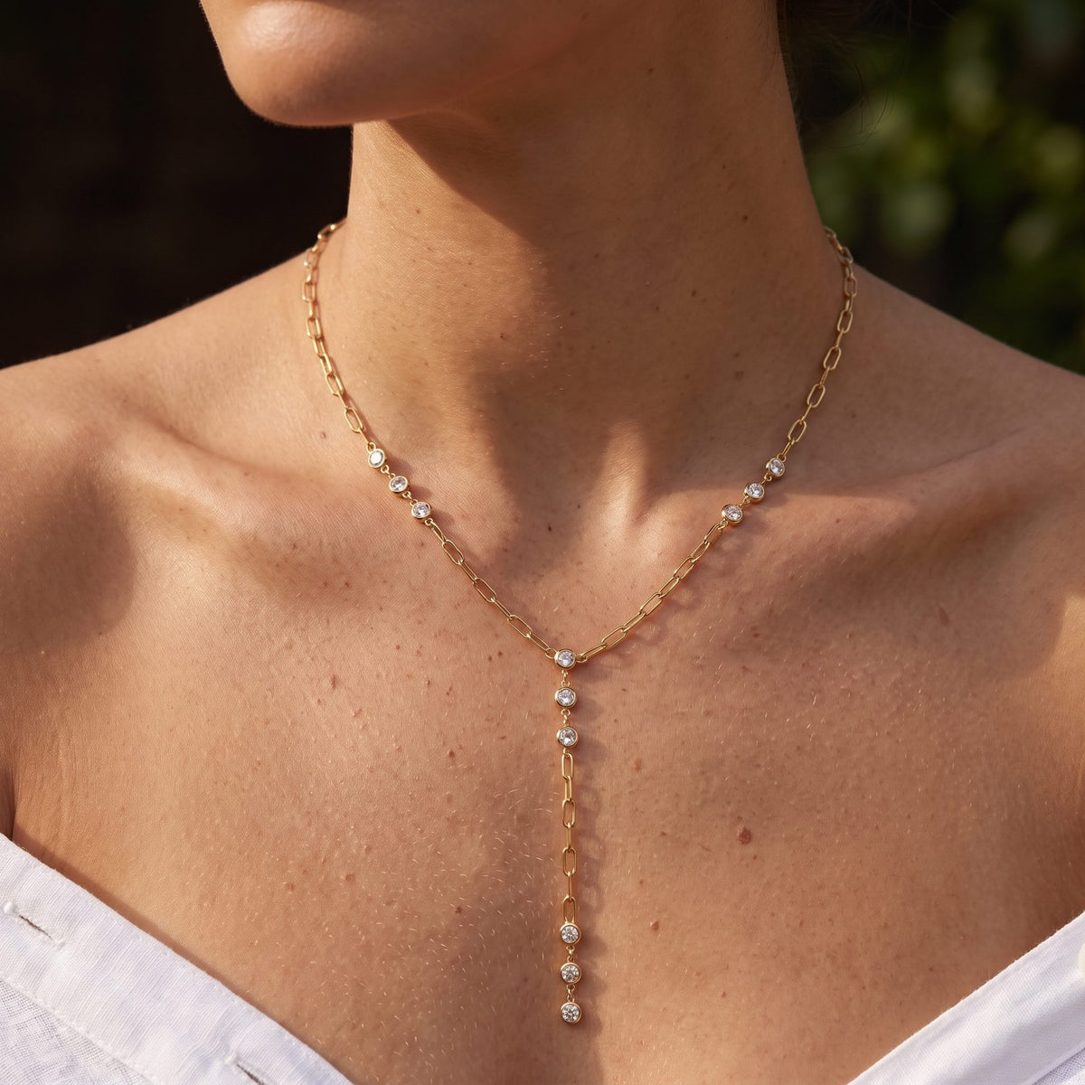 Woman wearing the Paperclip Lariat Necklace at the collarbone in warm sunlight