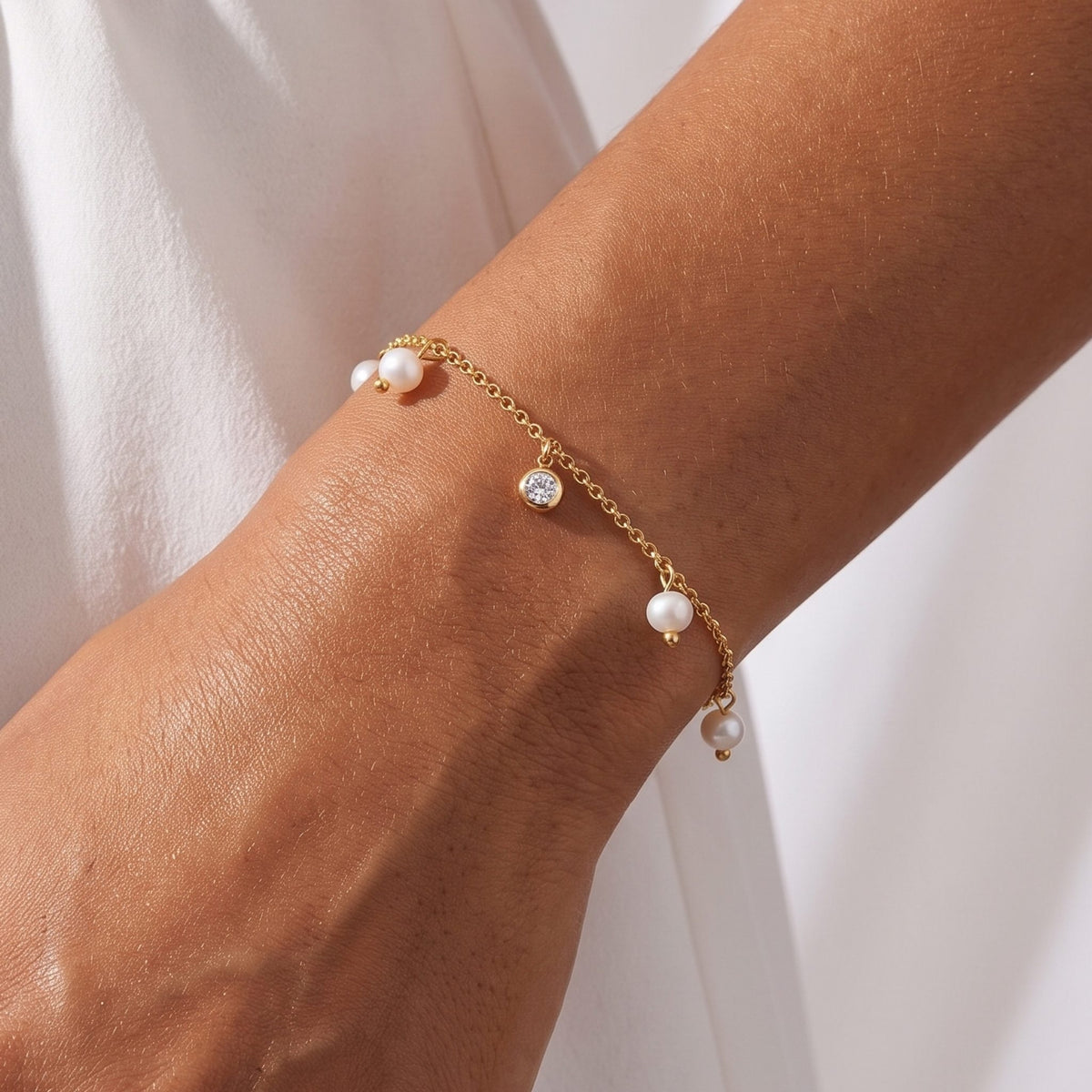 Close-up of the Pearl Charm Bracelet on the wrist, highlighting its dangling pearls and bezel-set crystal
