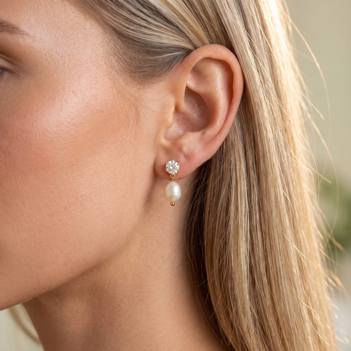 Woman wearing the Pearl Drop Earrings on the ear with her blonde hair tucked back