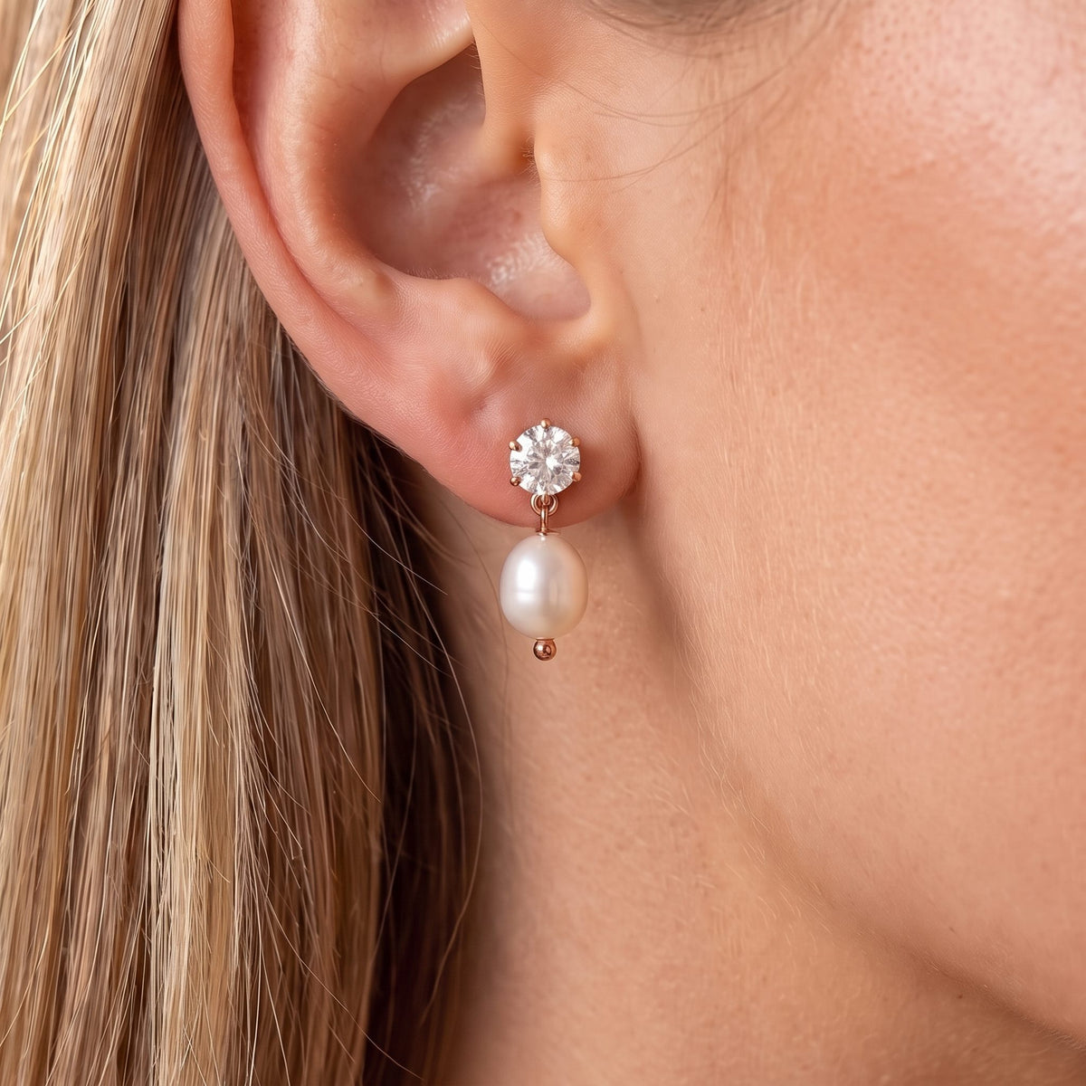Close-up of the Pearl Drop Earrings on the ear featuring a sparkling crystal stud and pearl, in rose gold
