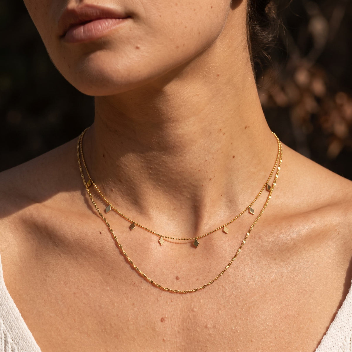 Woman wearing the Rhombus Drop Necklace on the neckline