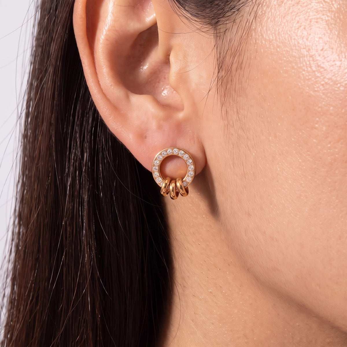 Close-up of the Ring Charm Studs on the ear showing crystal accents and small dangling rings, in rose gold