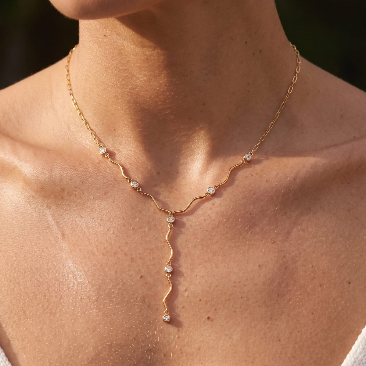 Close-up of the Ripple Lariat Necklace at the collarbone, highlighting its bezel-set crystals on a wavy chain