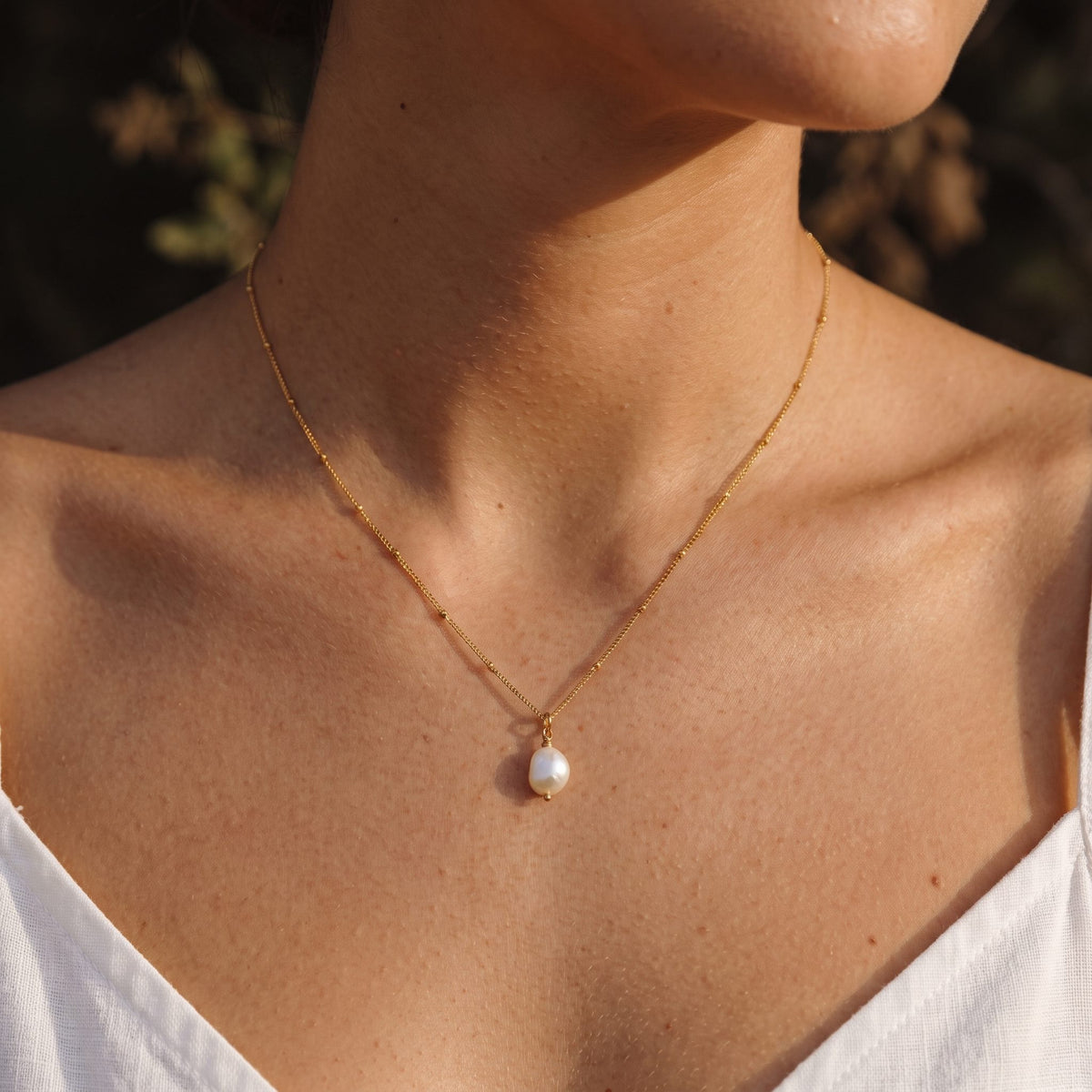 Wider view of a woman wearing the Round Pearl Pendant