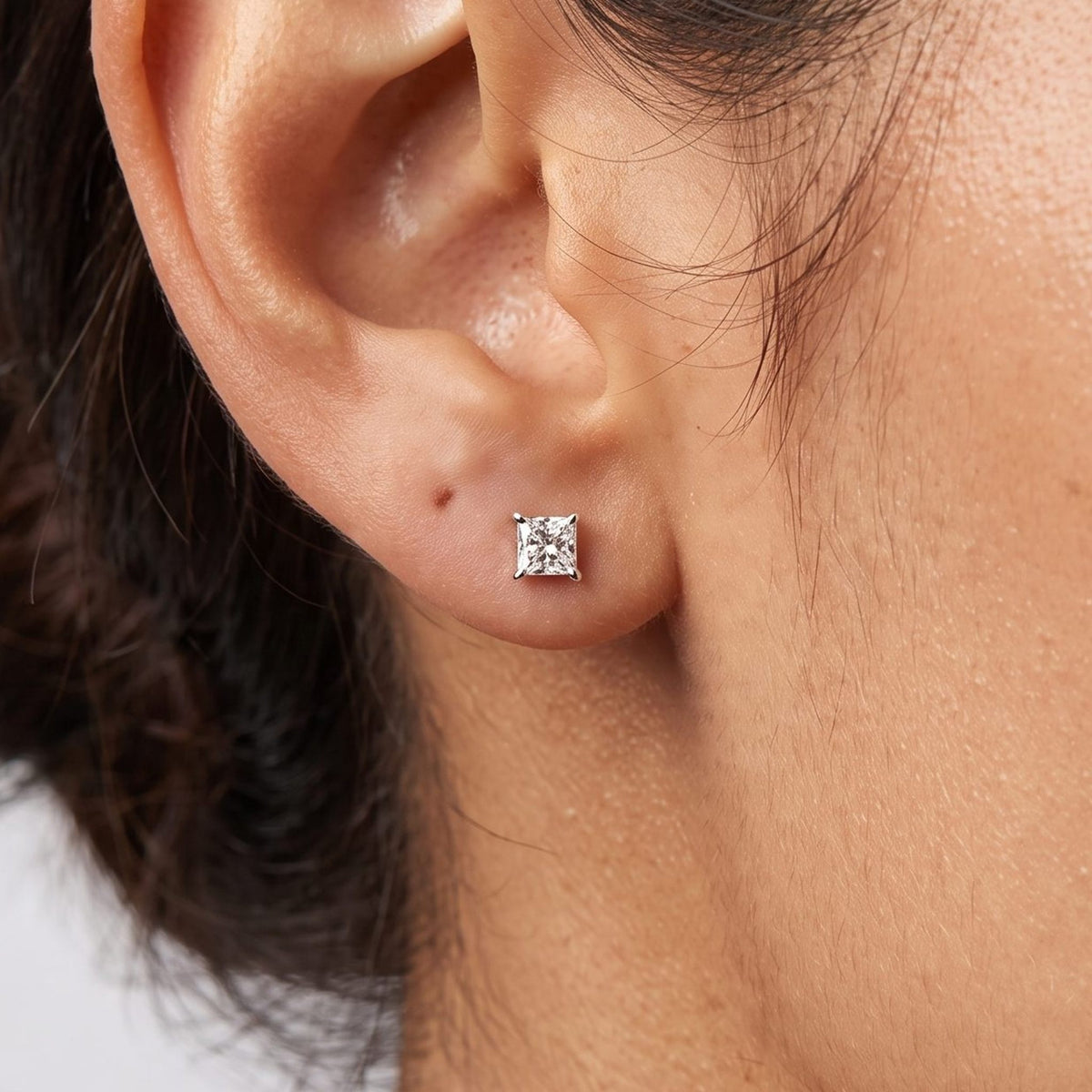 Close view of a woman wearing the Roxane Square Crystal Silver Studs flat to the lobe