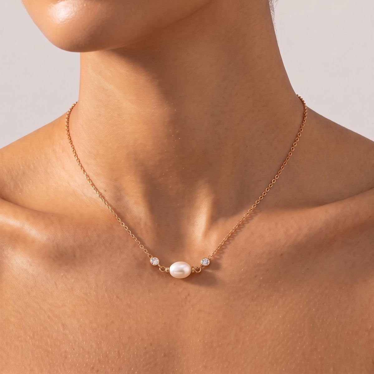 Close-up of the Sideways Pearl Necklace at the collarbone flanked by bezel-set crystals, in rose gold