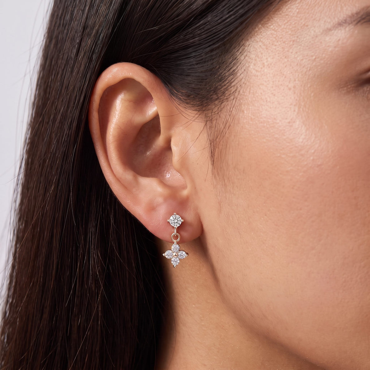 Woman wearing the Clover Earrings in rose gold, the clover hanging below a round crystal stud