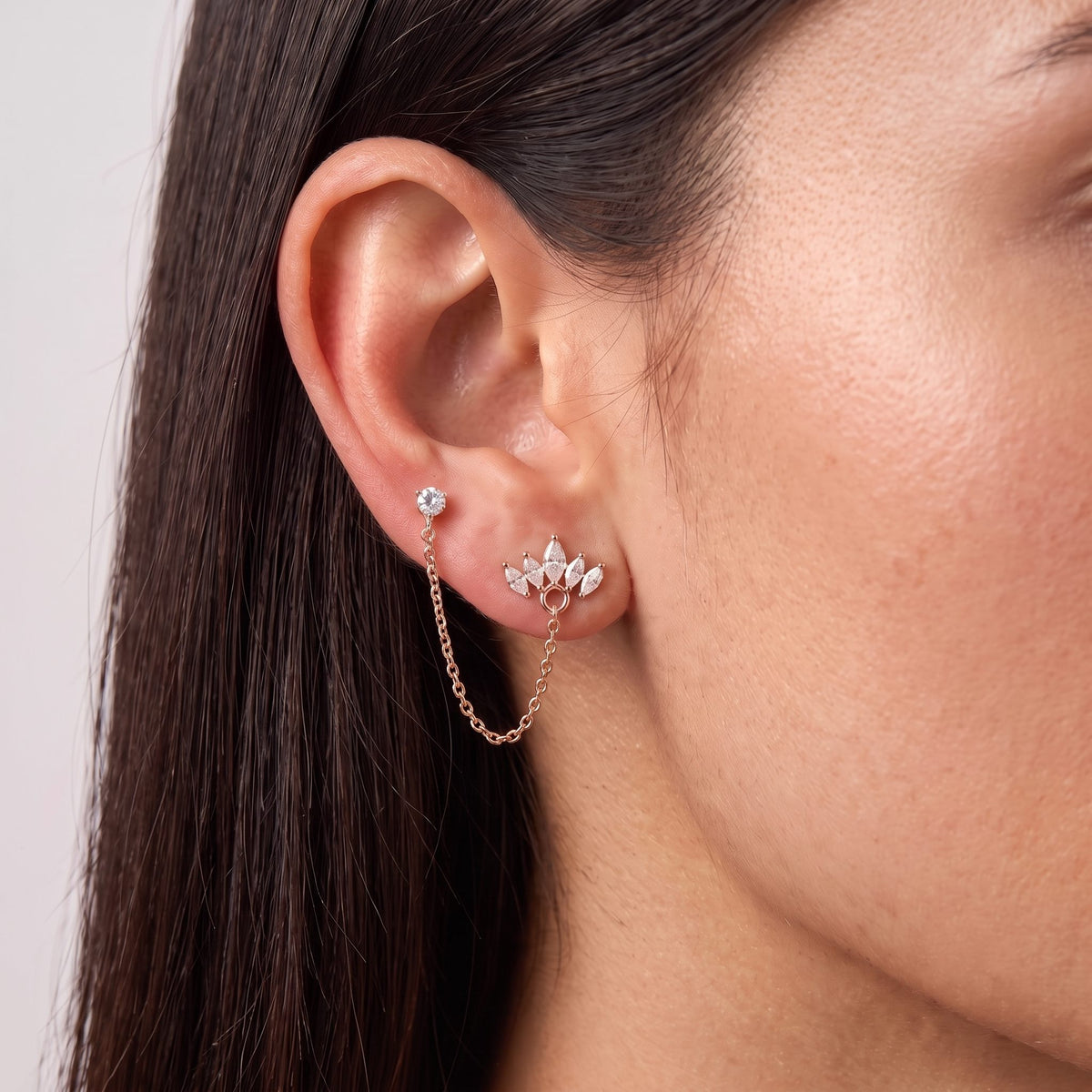 Woman wearing the Crown Earring in rose gold, the chain running up to a stud in a second piercing