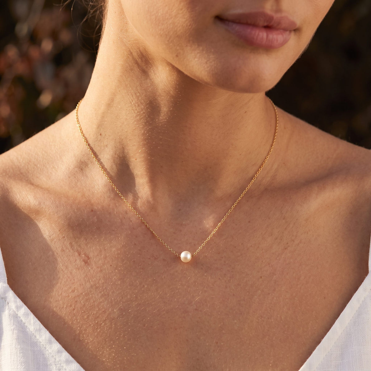 Wider view of a woman wearing the Single Pearl Pendant