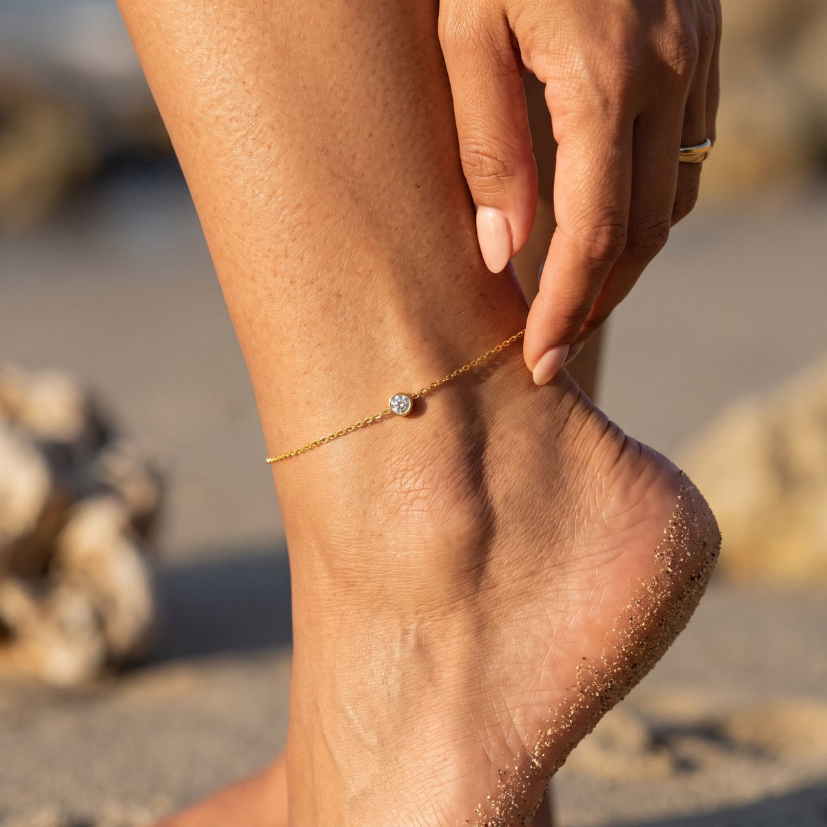Wider view of a woman wearing the Solitaire Anklet on her ankle