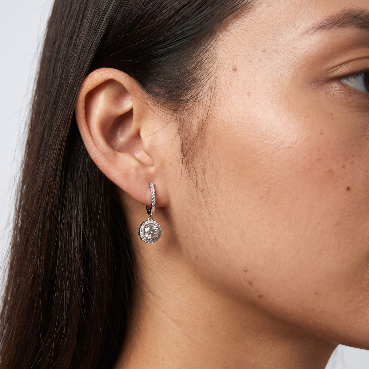 Woman wearing the Sophie Pavé Circle Earrings hanging below the lobe with a dangling silver round charm