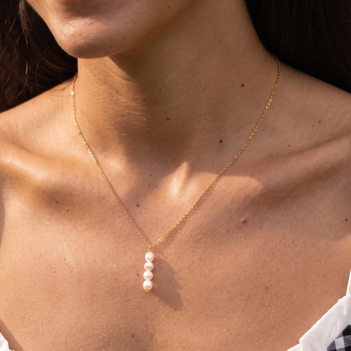 Close-up of the Stacked Pearl Pendant at the collarbone showing four pearls on a delicate gold chain