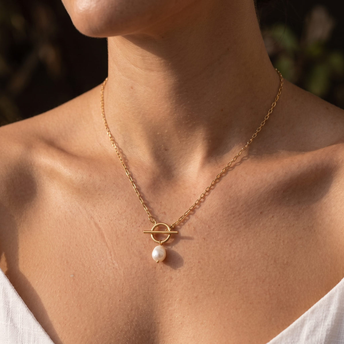 Woman wearing the Toggle Pearl Necklace on the neckline