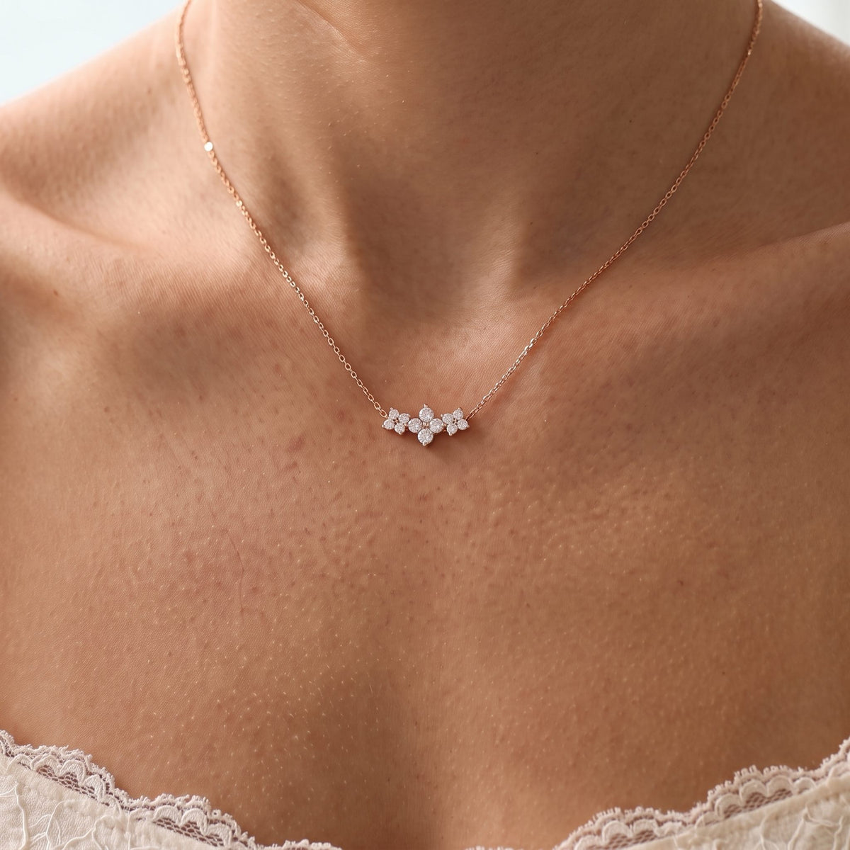 Close-up of the Triple Bloom Pendant worn on the neckline, in rose gold