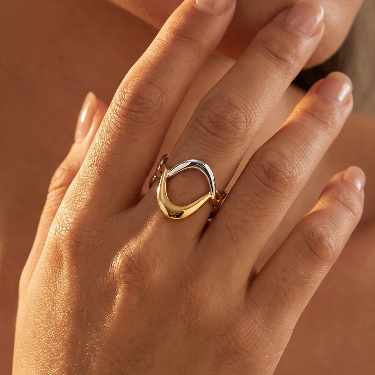 Close-up of the Two-Tone Twisted Wave Ring on her ring finger catching warm sunlight