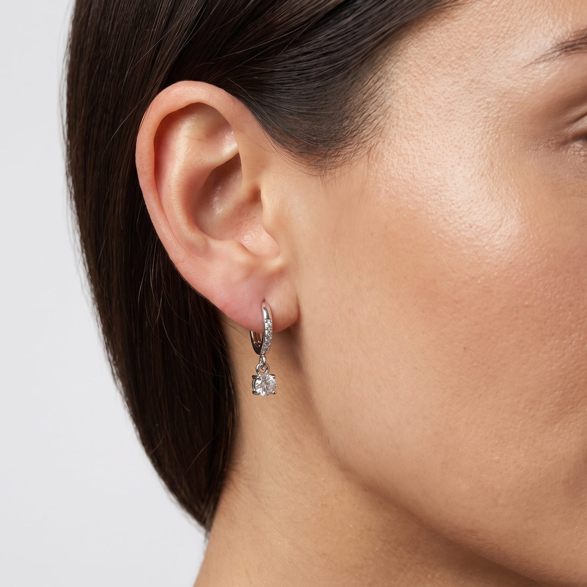 Woman wearing the Vittoria Crystal Silver Earrings hanging below the lobe with a dangling round crystal charm