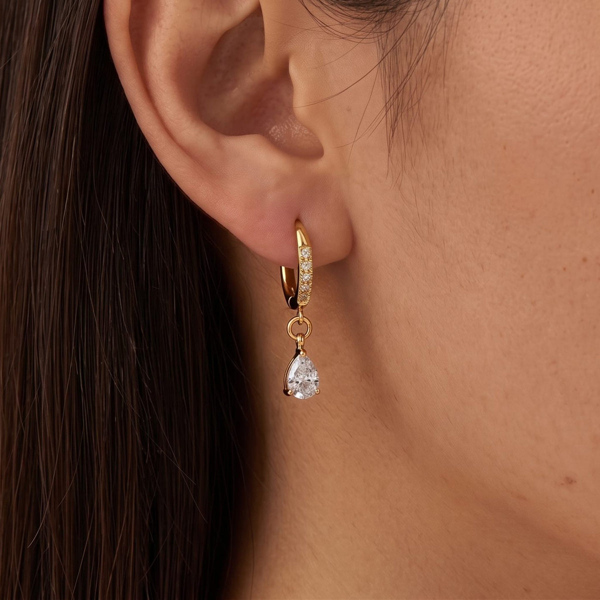 Woman wearing the Vittoria Crystal Water Drop Gold Earrings hanging below the lobe with a teardrop charm