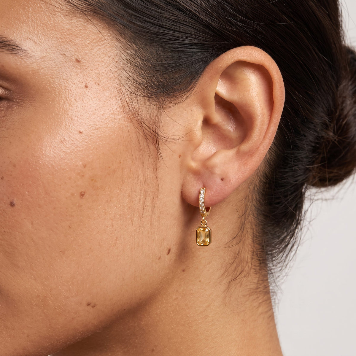 Woman wearing the Yellow Octagon Huggies on the ear with her hair pulled back into a bun